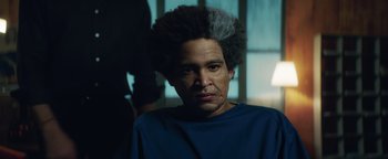 Movie still from “American Carnage” (2022), directed by Diego Hallivis – A man with a gray afro is looking at the camera; Close Up shot, Over the shoulder angle
