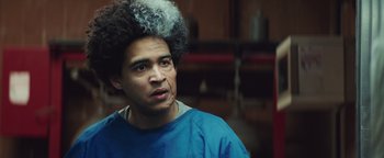 Movie still from “American Carnage” (2022), directed by Diego Hallivis – A man in a blue shirt is looking at the camera; Close Up shot, Over the shoulder angle