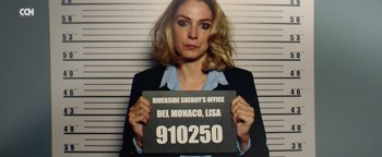 Movie still from “American Carnage” (2022), directed by Diego Hallivis – A woman holding up a sign that says " 9 1 0 2 5 0 "; Close Up shot, Low angle