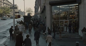 Movie still from “American Gangster” (2007), directed by Ridley Scott – A crowd of people walking down a sidewalk near a building; Extreme Wide shot, High angle