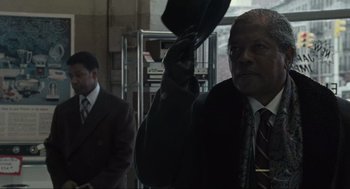 Movie still from “American Gangster” (2007), directed by Ridley Scott – A man in a suit and tie holding an umbrella in front of another man in a suit and tie; Close Up shot, Low angle