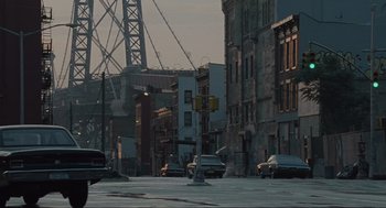 Movie still from “American Gangster” (2007), directed by Ridley Scott – Cars parked on the side of the road in a city; Extreme Wide shot, High angle