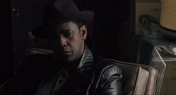 Movie still from “American Gangster” (2007), directed by Ridley Scott – A man wearing a black hat and leather jacket; Close Up shot, Over the shoulder angle
