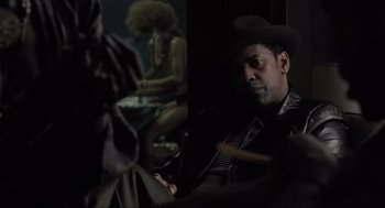 Movie still from “American Gangster” (2007), directed by Ridley Scott – A man in a cowboy hat sitting next to a woman; Medium shot, Over the shoulder angle