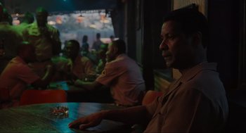 Movie still from “American Gangster” (2007), directed by Ridley Scott – A group of people sitting at a table in a room; Medium shot, Over the shoulder angle