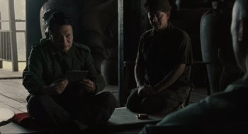 Movie still from “American Gangster” (2007), directed by Ridley Scott – Two men sitting on the ground looking at a tablet computer; Medium shot, Over the shoulder angle