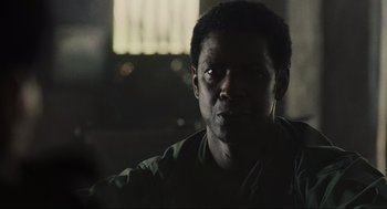Movie still from “American Gangster” (2007), directed by Ridley Scott – A person in a dark room; Close Up shot, Over the shoulder angle