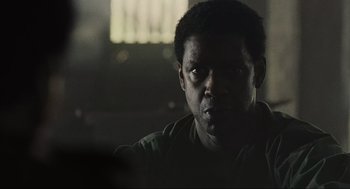 Movie still from “American Gangster” (2007), directed by Ridley Scott – A person in a dark room; Close Up shot, Over the shoulder angle