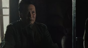 Movie still from “American Gangster” (2007), directed by Ridley Scott – A man in military fatigues sitting in a dark room; Close Up shot, Over the shoulder angle