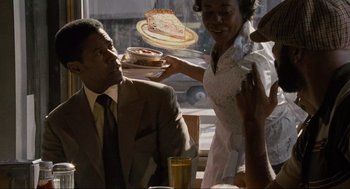 Movie still from “American Gangster” (2007), directed by Ridley Scott – A man and a woman holding a piece of cake; Medium shot, Over the shoulder angle