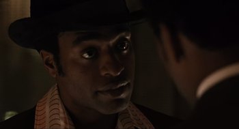 Movie still from “American Gangster” (2007), directed by Ridley Scott – A person wearing a hat; Close Up shot, Over the shoulder angle