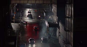 Movie still from “American Gangster” (2007), directed by Ridley Scott – Cars driving down a street at night in the rain; Extreme Wide shot, High angle