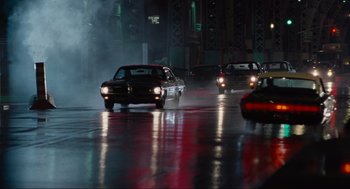Movie still from “American Gangster” (2007), directed by Ridley Scott – A group of cars driving down a wet street; Wide shot, High angle