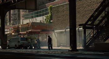 Movie still from “American Gangster” (2007), directed by Ridley Scott – A man standing on the side of the street; Extreme Wide shot, High angle