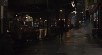 Movie still from “American Gangster” (2007), directed by Ridley Scott – A man walking down a street at night; Extreme Wide shot, High angle