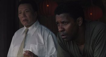 Movie still from “American Gangster” (2007), directed by Ridley Scott – Two men sitting next to each other in front of a lamp; Close Up shot, Over the shoulder angle