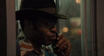 Movie still from “American Gangster” (2007), directed by Ridley Scott – A man in a hat is talking on a cell phone; Close Up shot, Low angle