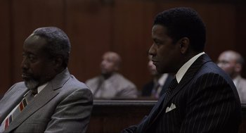 Movie still from “American Gangster” (2007), directed by Ridley Scott – Two men in suits sitting in a courtroom; Medium shot, Over the shoulder angle