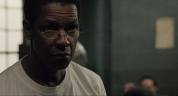 Movie still from “American Gangster” (2007), directed by Ridley Scott – A person wearing glasses and a white shirt; Close Up shot, Over the shoulder angle