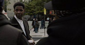 Movie still from “American Gangster” (2007), directed by Ridley Scott – A man in a suit is holding a cup of coffee; Close Up shot, Over the shoulder angle