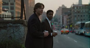 Movie still from “American Gangster” (2007), directed by Ridley Scott – A couple of men standing next to each other on the side of a road; Medium shot, Over the shoulder angle