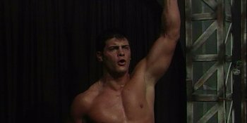 Movie still from “American Nightmare: Becoming Cody Rhodes” (2023), directed by Matt Braine – A shirtless man raises his arm in the air; Medium shot, Low angle