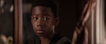 Movie still from “The Hate U Give” (2018), directed by George Tillman Jr. – A young man's face in a dark room; Close Up shot, Over the shoulder angle