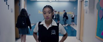 Movie still from “The Hate U Give” (2018), directed by George Tillman Jr. – A girl in a school uniform standing in front of a group of people; Medium shot, Over the shoulder angle