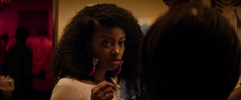 Movie still from “The Hate U Give” (2018), directed by George Tillman Jr. – A young woman with long black hair wearing large pink earrings; Close Up shot, Over the shoulder angle