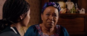 Movie still from “The Hate U Give” (2018), directed by George Tillman Jr. – An older woman wearing a head scarf looking sad; Close Up shot, Over the shoulder angle