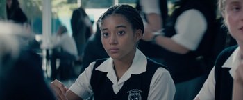 Movie still from “The Hate U Give” (2018), directed by George Tillman Jr. – A girl in a school uniform is looking into the camera; Close Up shot, High angle