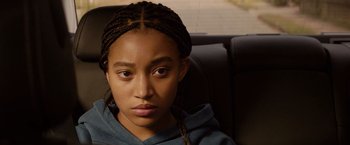 Movie still from “The Hate U Give” (2018), directed by George Tillman Jr. – A young girl sitting in a car looking at the camera; Close Up shot, Over the shoulder angle