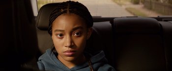 Movie still from “The Hate U Give” (2018), directed by George Tillman Jr. – A young girl sitting in a car looking at the camera; Close Up shot, Over the shoulder angle