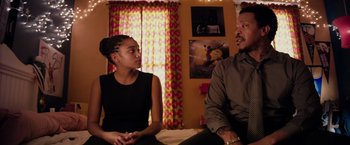 Movie still from “The Hate U Give” (2018), directed by George Tillman Jr. – A man and a woman sitting on a bed in front of a window; Medium shot, Over the shoulder angle