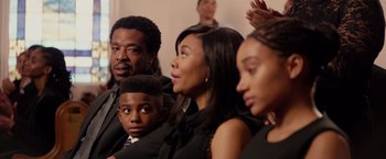 Movie still from “The Hate U Give” (2018), directed by George Tillman Jr. – A group of people sitting next to each other in a room; Medium shot, Over the shoulder angle