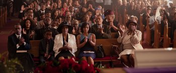 Movie still from “The Hate U Give” (2018), directed by George Tillman Jr. – A group of people sitting in a room clapping; Wide shot, High angle
