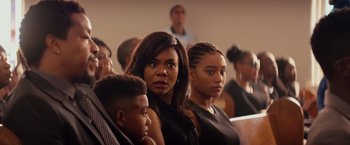 Movie still from “The Hate U Give” (2018), directed by George Tillman Jr. – A group of people sitting in a room; Medium shot, Over the shoulder angle