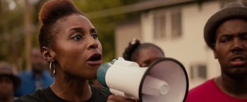 Movie still from “The Hate U Give” (2018), directed by George Tillman Jr. – A woman holding a megaphone up to her mouth; Close Up shot, Low angle