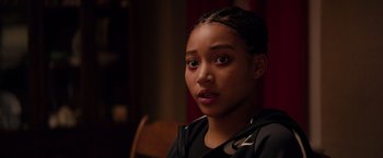 Movie still from “The Hate U Give” (2018), directed by George Tillman Jr. – A young woman with a black shirt and a black jacket is looking at the camera; Close Up shot, Over the shoulder angle