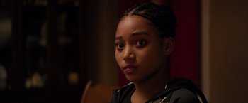Movie still from “The Hate U Give” (2018), directed by George Tillman Jr. – A young woman sitting in front of a wooden chair; Close Up shot, Over the shoulder angle