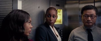 Movie still from “The Hate U Give” (2018), directed by George Tillman Jr. – A woman in a business suit standing in front of an elevator; Medium shot, Over the shoulder angle