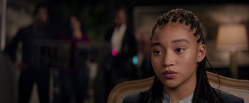 Movie still from “The Hate U Give” (2018), directed by George Tillman Jr. – A young girl with braids sitting in front of a group of people; Close Up shot, Over the shoulder angle