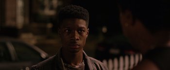 Movie still from “The Hate U Give” (2018), directed by George Tillman Jr. – A young man with a black shirt is looking at the camera; Close Up shot, Over the shoulder angle