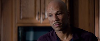 Movie still from “The Hate U Give” (2018), directed by George Tillman Jr. – A man with a bald head looking at the camera; Close Up shot, High angle