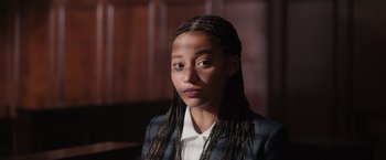 Movie still from “The Hate U Give” (2018), directed by George Tillman Jr. – A young woman with long braids wearing a suit; Close Up shot, Over the shoulder angle