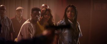 Movie still from “The Hate U Give” (2018), directed by George Tillman Jr. – A group of people standing next to each other in a room; Medium shot, Over the shoulder angle