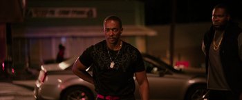 Movie still from “The Hate U Give” (2018), directed by George Tillman Jr. – A man standing in front of a car on a city street; Medium shot, Over the shoulder angle