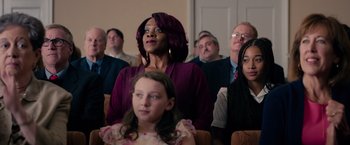 Movie still from “The Hate U Give” (2018), directed by George Tillman Jr. – A group of people sitting in a room watching something; Medium shot, Over the shoulder angle