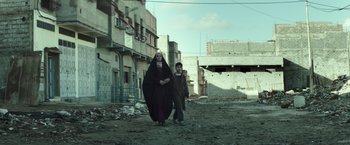 Movie still from “American Sniper” (2014), directed by Clint Eastwood – A woman and a boy are walking down the street; Wide shot, Low angle