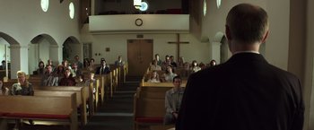 Movie still from “American Sniper” (2014), directed by Clint Eastwood – A group of people sitting in a church; Wide shot, Low angle